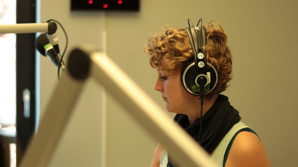 Frau mit Kopfhörern im Radiostudio