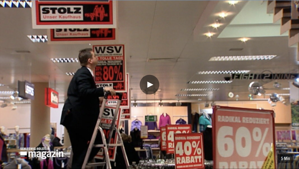 Verkäufer steht in Kaufhaus auf Leiter vor WSV-Schildern